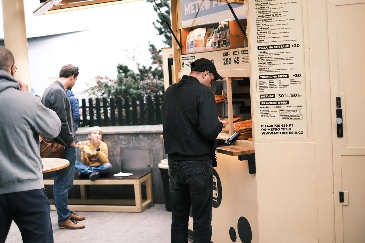 Zákazník platí u budky Metro Pizza