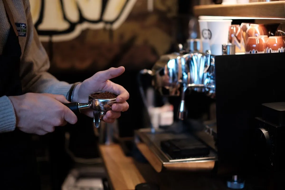 Barista pěchuje čerstvě namletou kávu u páky