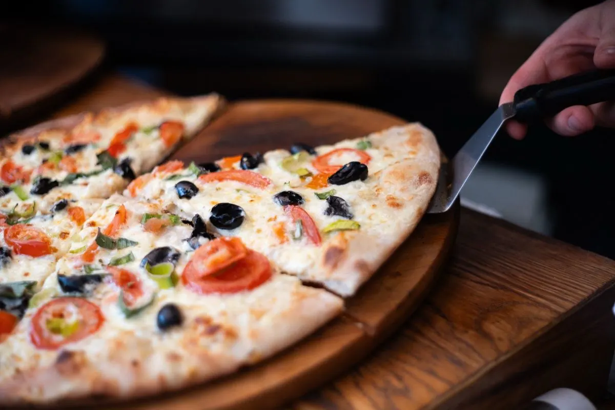 Pizza na dřevěném prkénku s nožem na krájení